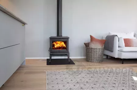 Estufa Jøtul F100 ECO SE instalada en una sala de estar, irradiando calor con su diseño escandinavo.