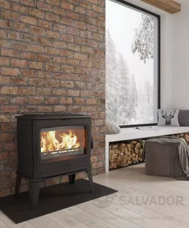 La Dovre Tai 55WD iluminando un salón rústico con paredes de piedra y decoración cálida.