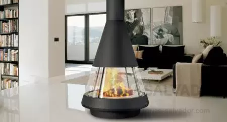 Chimenea metálica Hergom Mallorca con diseño moderno y cristal panorámico curvo, instalada en salón contemporáneo.